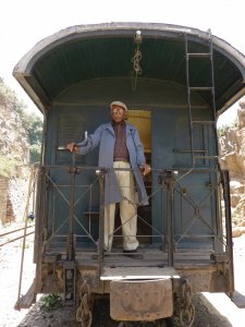 Le mécanicien du train à vapeur se tient fièrement à l'arrière de sa machine adorée.