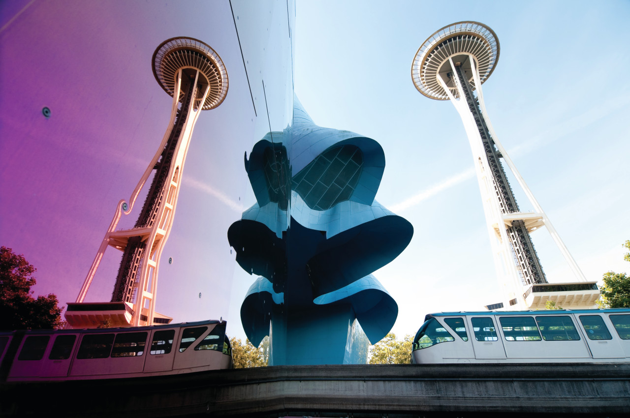 Seattle, USA - September 19, 2013 : The Seattle Monorail entering the Seattle Center through the Experience Music Project with a reflection of the Space Needle on a sunny day. The Monorail was originally built in 1962 for the Worlds Fair.